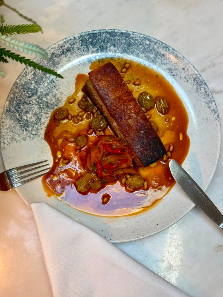 Crispy Pork Belly with Peperonata, Golden Raisins and Pine Nuts